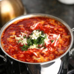 Fresh dill and garlic added on top of simmering borscht