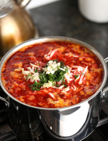 Fresh dill and garlic added on top of simmering borscht